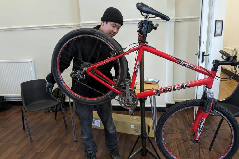 A young man fixing a bike indoors