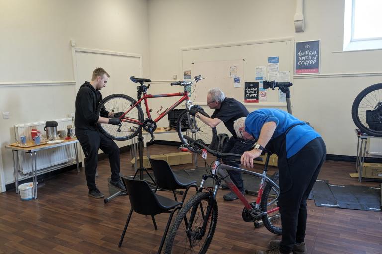 Three men fixing bikes