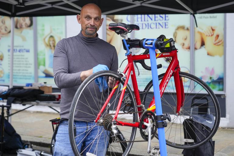 A man stood outdoors fixing a bike