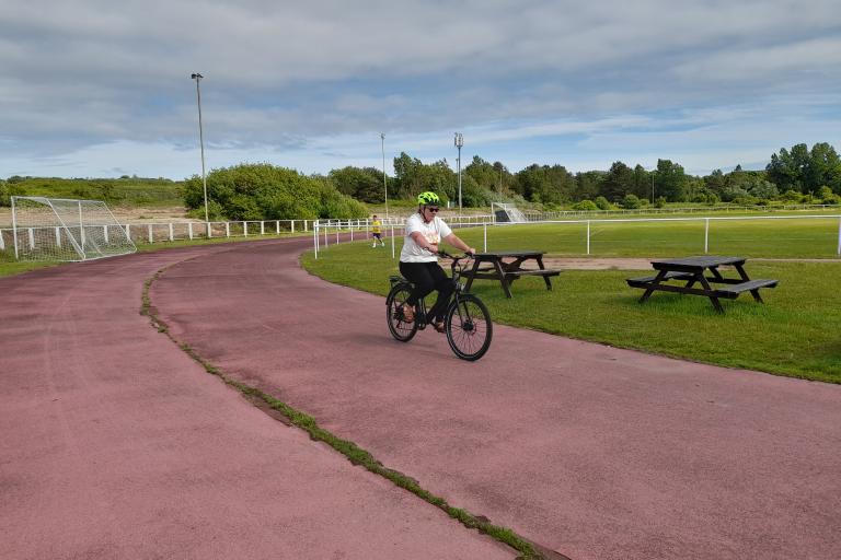A lady riding an e-bike on a cycle track