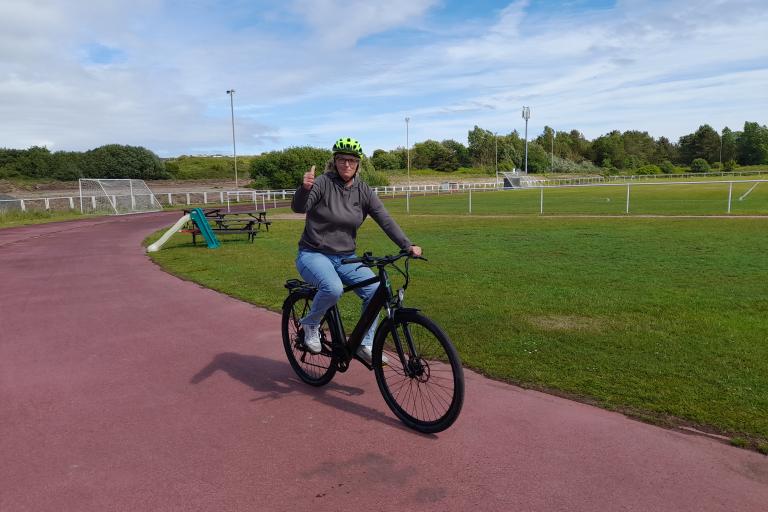 A lady riding an e-bike on a cycle track