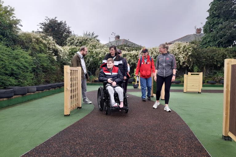 A group of adults with special needs walking outdoors in a garden