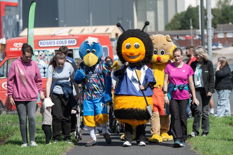 A group including people dressed in mascot costumes walking outdoors