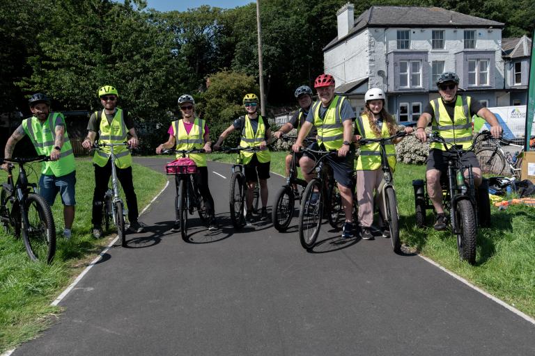 A group of cyclists stood with bikes in a group wearing high vis jackets