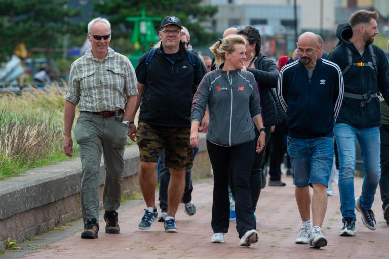A group of adults walking outdoors in Barrow along the channel