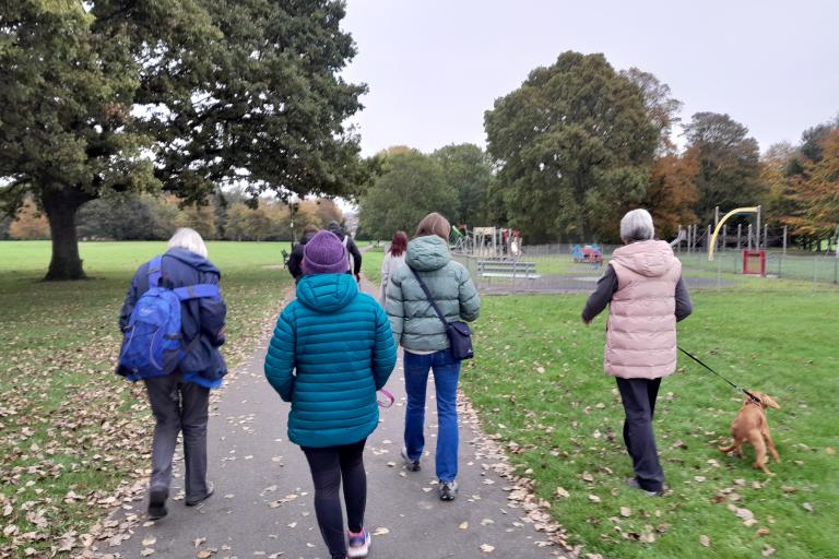 A group of adults walking outdoors in a park in Carlisle