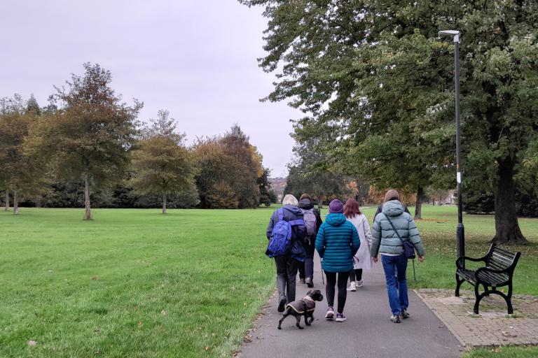 A group of adults walking outdoors in a park in Carlisle