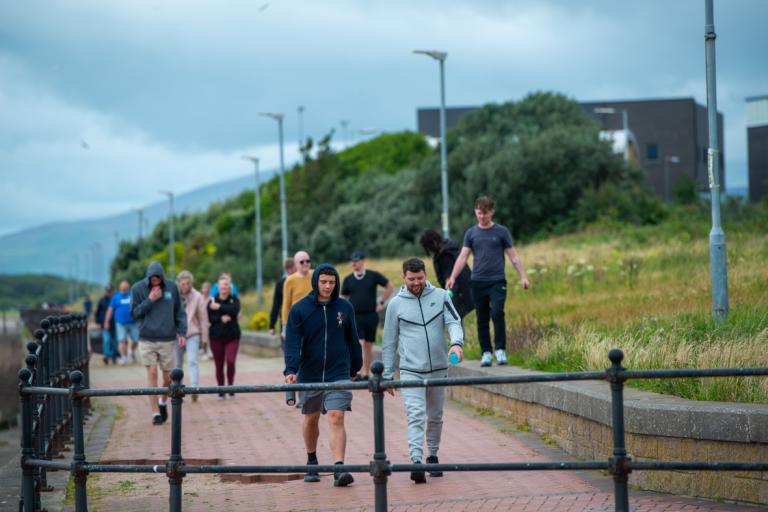 a group of adults walking outdoors along the channelside 