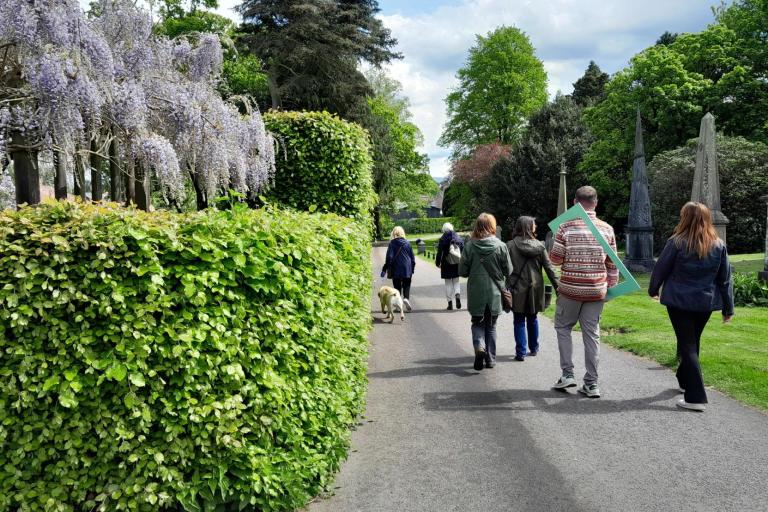 a group of people walking outdoors through a park.