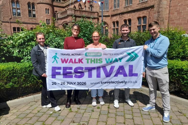 a group of adults standing holding an advertising banner