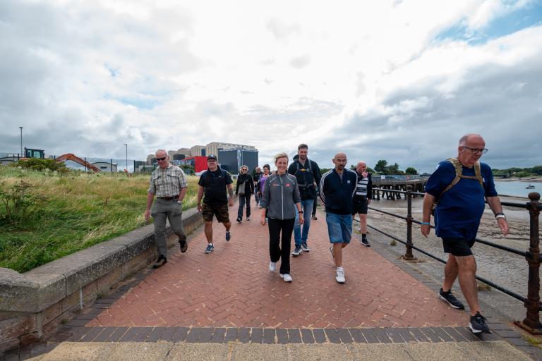 a group of adults walking outdoors along the channelside 