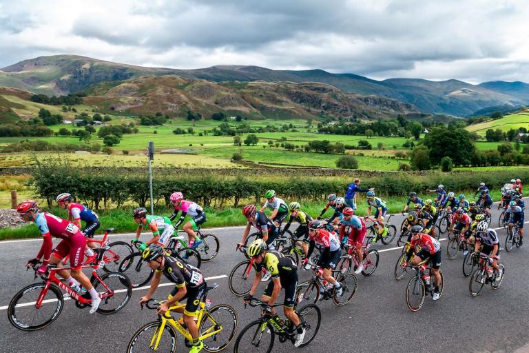 a group of cyclists taking part in a race with lake district fells in the background 