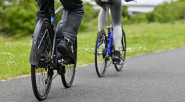 Two cyclists cycling down a path