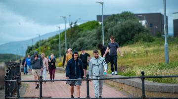 a group of adults walking outdoors along the channelside 