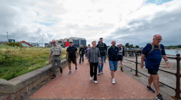 a group of adults walking outdoors along the channelside 