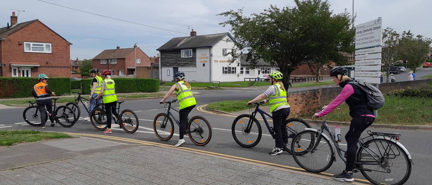 A group of mixed adults and children cycling on a road