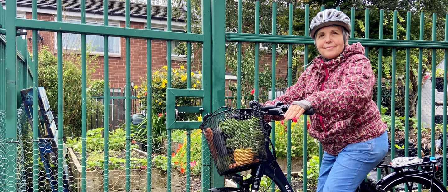 Woman on an electric bike with vegetables in a basket.