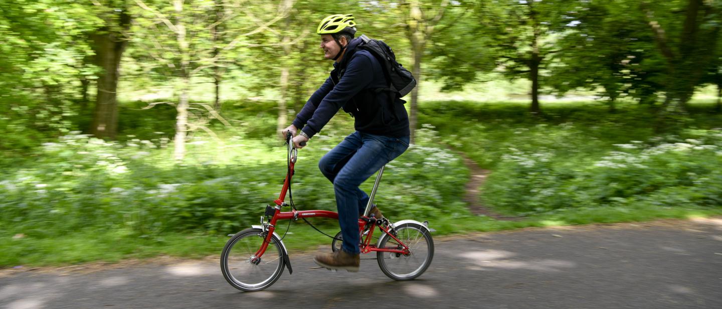 Man riding a red bike through a park
