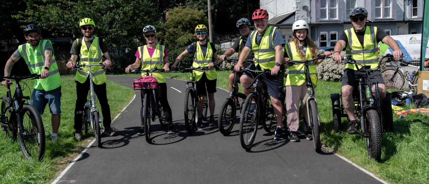 A group of cyclists stood with bikes in a group wearing high vis jackets